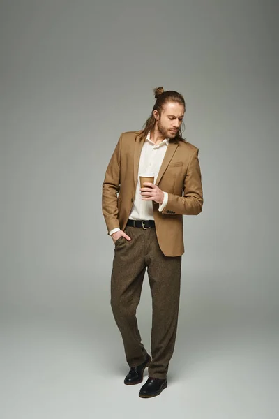 Bel homme d'affaires avec barbe et cheveux longs tenant café pour aller sur fond gris, tenue formelle — Photo de stock