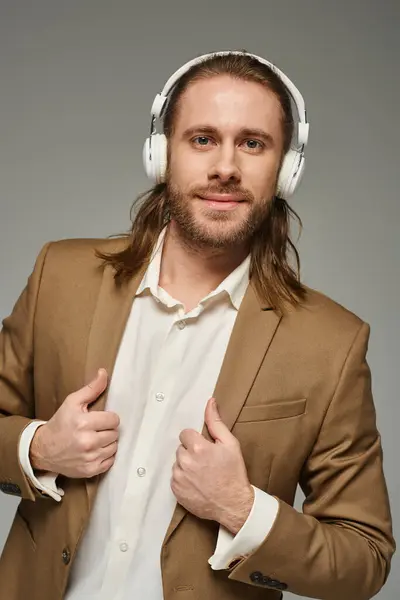 Веселий бородатий бізнесмен в навушниках слухає музику на сірому фоні, формальний одяг — стокове фото