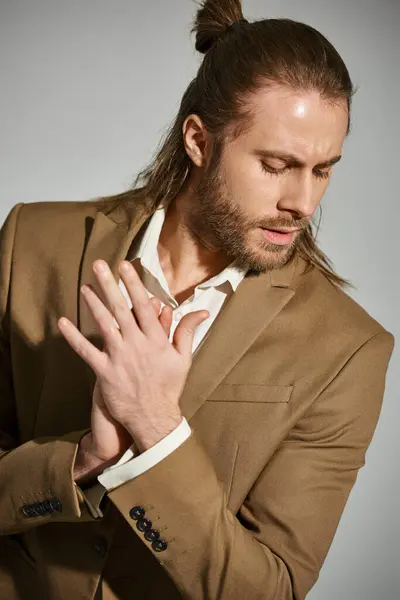 Portrait of good looking businessman in white shirt and stylish beige blazer on grey background — Stock Photo