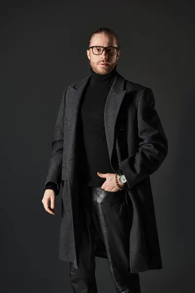 Uomo barbuto in occhiali e cappotto di lana di classe in posa con mano in tasca su sfondo grigio — Foto stock