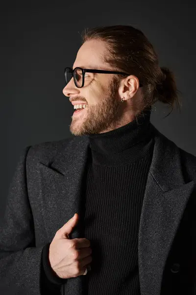 Cheerful man in eyeglasses and classy woolen coat laughing and looking away on grey background — Stock Photo