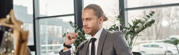 Serio uomo d'affari orientato al lavoro in giacca e cravatta grigia seduto e pensando sul posto di lavoro in ufficio, banner — Foto stock