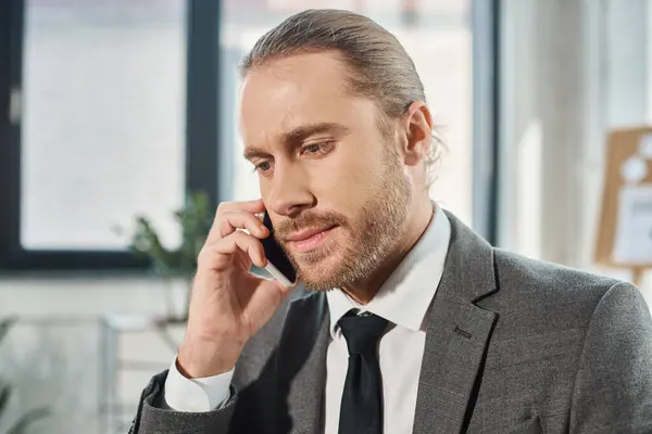 Homme d'affaires sérieux et concentré parlant sur téléphone portable dans le bureau moderne, résolution de problèmes — Photo de stock