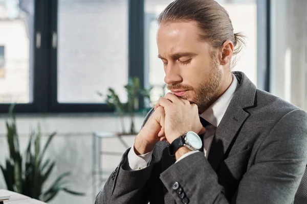Ritratto di uomo d'affari esausto in abito grigio con gli occhi chiusi e le mani vicino al mento in ufficio — Foto stock