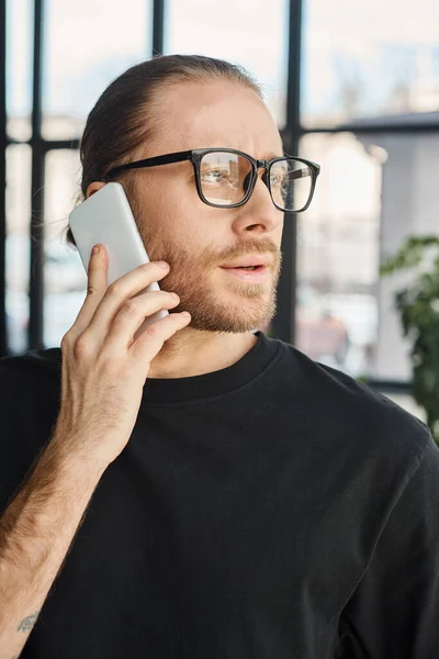 Ritratto di elegante uomo d'affari in occhiali che parla sul cellulare e distoglie lo sguardo in ufficio — Foto stock