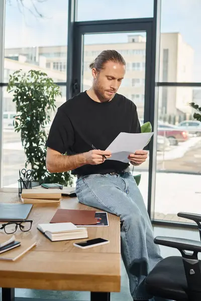 Manager in abbigliamento casual seduto sulla scrivania vicino ai quaderni e guardando documenti, documenti — Foto stock
