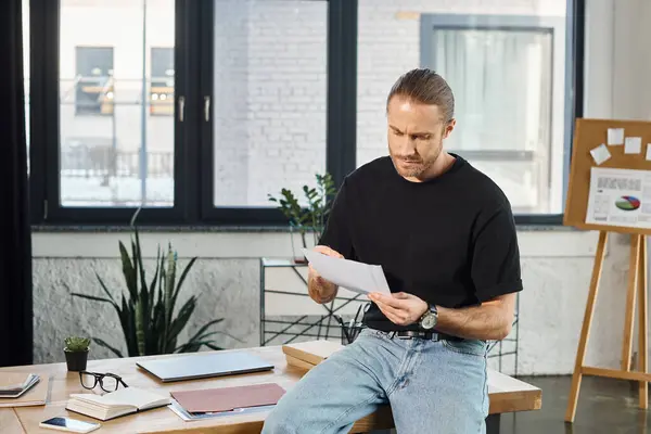 Manager premuroso in abbigliamento casual seduto sulla scrivania e guardando i documenti in ufficio — Foto stock