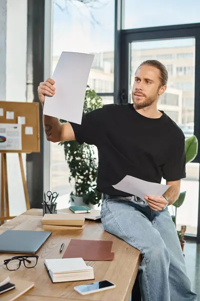 Hombre de negocios serio en ropa casual sentado en el escritorio de trabajo cerca y papel en la oficina moderna - foto de stock