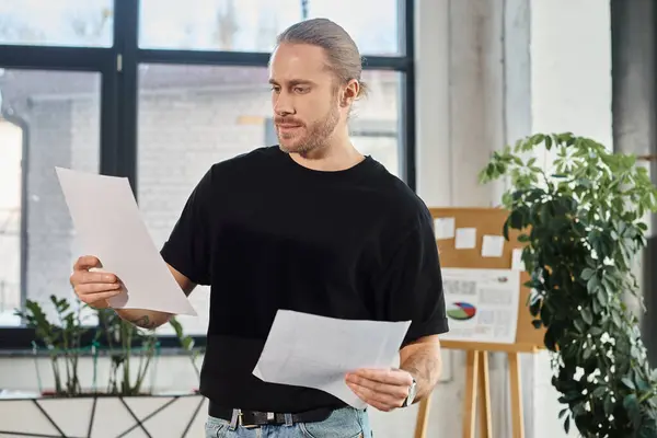 Uomo d'affari premuroso in abbigliamento casual guardando i documenti e pensando in ufficio moderno, documenti — Foto stock