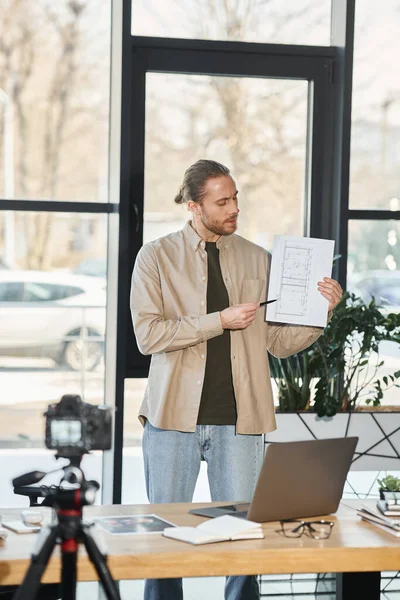 Creative manager in casual attire showing blue print during video presentation in modern office — Stock Photo