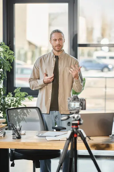 Творческий бизнесмен разговаривает перед цифровой камерой во время видеоблога в офисе, маркетинга — стоковое фото