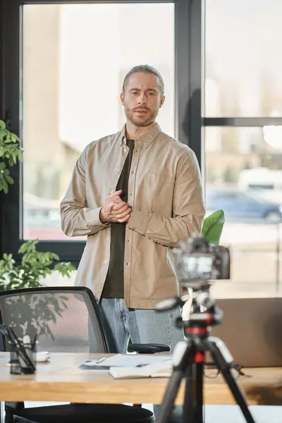 Стильный бизнесмен в повседневной одежде записывает видео блог на цифровую камеру в современном офисе — стоковое фото