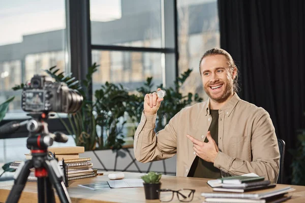 Lächelnder erfolgreicher Unternehmer zeigt Bitcoin während Videoblog am Arbeitsplatz in modernem Büro — Stockfoto