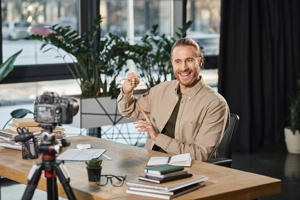 Happy businessman pointing at bitcoins and recording video blog on digital camera in office — Stock Photo