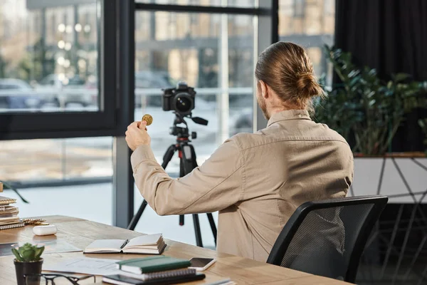 Visão traseira do empresário de sucesso mostrando bitcoin na câmera digital na mesa de trabalho no escritório moderno — Fotografia de Stock