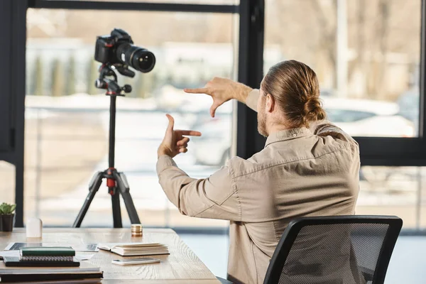 Rückansicht eines Geschäftsmannes, der am Arbeitsplatz im Büro vor der Digitalkamera gestikuliert, Videoblogger — Stockfoto