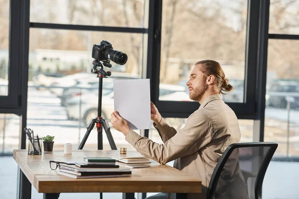Seitenansicht des Managers in Freizeitkleidung, der während eines Videoblogs im Büro Dokument an der Digitalkamera zeigt — Stockfoto
