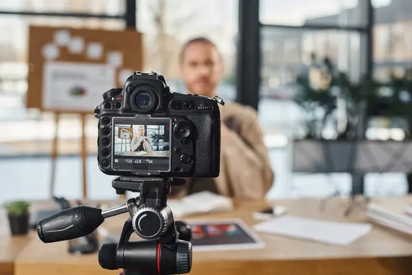 Selective focus of professional digital camera near businessman recording video content in office — Stock Photo