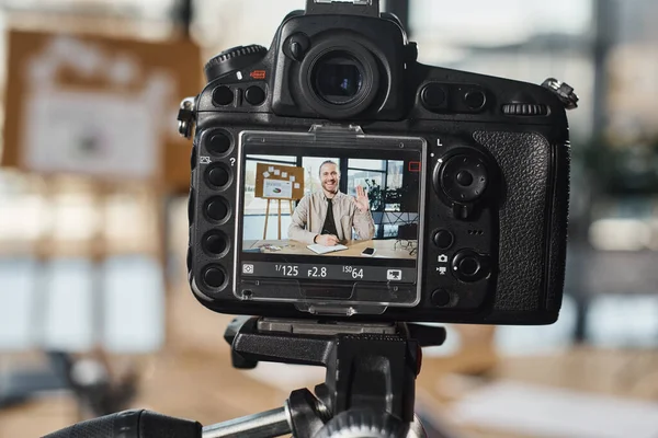 Close up view of digital camera near cheerful businessman recording video content in modern office — Stock Photo