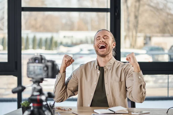 Empresário feliz mostrando gesto de vitória na frente da câmera digital durante vídeo blog no escritório — Fotografia de Stock