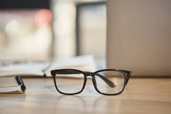 Óculos elegantes na mesa de trabalho no escritório contemporâneo em fundo borrado, moda de negócios — Fotografia de Stock