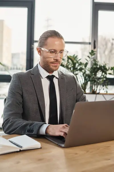 Empresário concentrado em óculos e desgaste formal trabalhando no laptop no espaço de escritório moderno — Fotografia de Stock