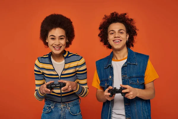 Good looking african american brother and sister playing video games with joysticks, family concept — Stock Photo