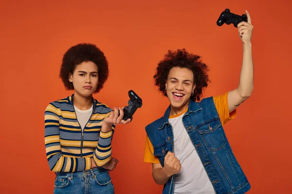 Молодые африканские американский брат и сестра играют в видеоигры с джойстиками, семейная концепция — стоковое фото