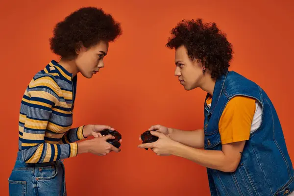 Elegante hermano afroamericano y hermana jugando videojuegos con joystick, concepto de familia - foto de stock