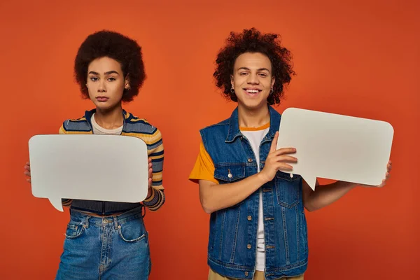 Attractive young african american siblings in urban attire with speech bubbles on orange backdrop — Stock Photo