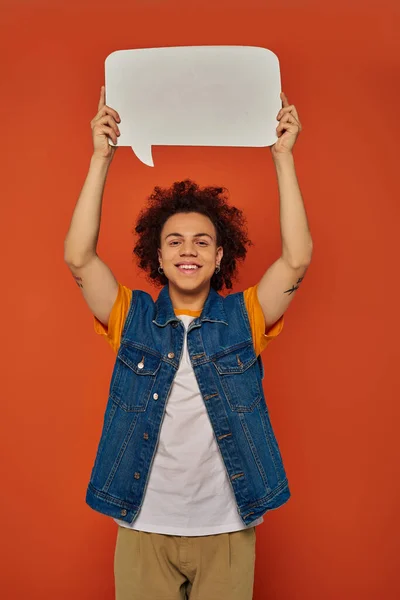 Alegre afro-americano masculino modelo em roupas casuais posando com bolha de fala no fundo laranja — Fotografia de Stock