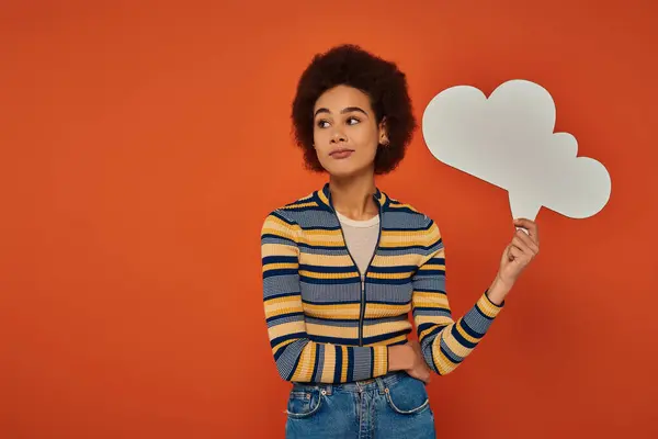 Attractive african american woman in urban attire posing with thought bubble on orange backdrop — Stock Photo
