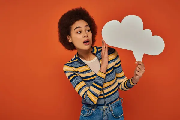 Hermosa mujer afroamericana en traje urbano posando con burbuja de pensamiento sobre fondo naranja — Stock Photo