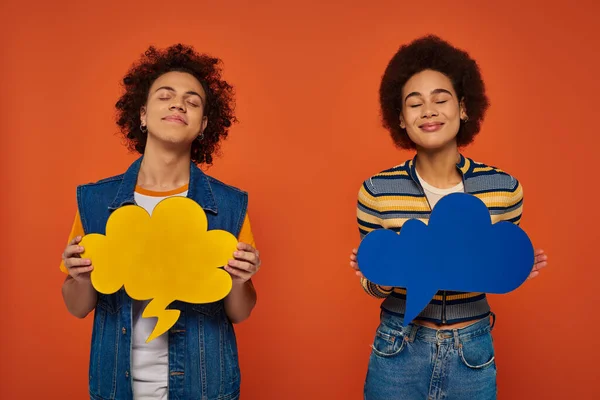 Bom olhar afro-americano irmão e irmã posando com bolhas de pensamento em pano de fundo laranja — Fotografia de Stock