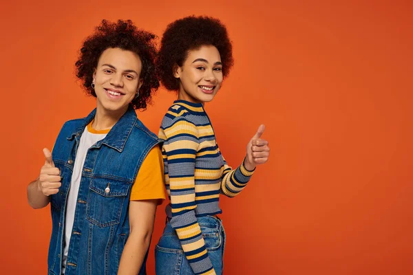 Joyous attractive african american siblings posing together and gesturing on orange backdrop — Stock Photo