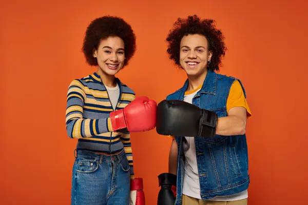Alegre afroamericano hermanos en guantes de boxeo divertirse juntos en naranja telón de fondo, familia - foto de stock