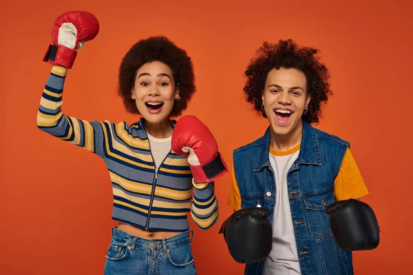 Fröhlich afrikanisch-amerikanische Geschwister in Boxhandschuhen haben gemeinsam Spaß auf orangefarbener Kulisse, Familie — Stockfoto