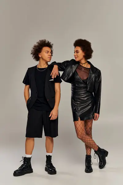 Attraktive lächelnde afrikanisch-amerikanische Geschwister in modischen schwarzen Outfits posieren aktiv miteinander — Stockfoto