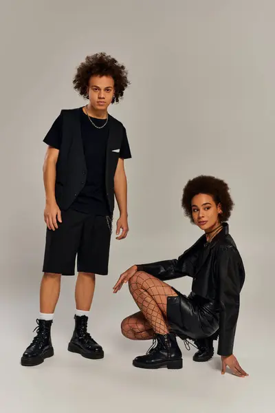 Attrayants frères et sœurs afro-américains élégants dans des tenues noires à la mode posant activement ensemble — Photo de stock