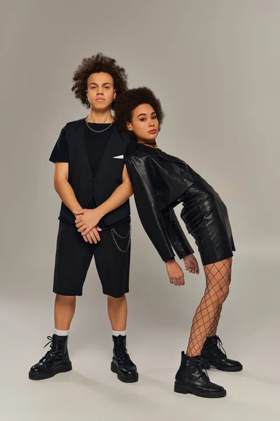 Attractive stylish african american siblings in fashionable black outfits posing on gray backdrop — Stock Photo