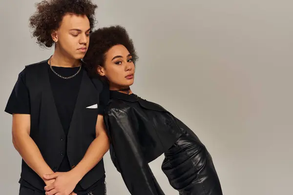 Ansprechend stylische afrikanisch-amerikanische Geschwister in modischer schwarzer Kleidung posieren vor grauem Hintergrund — Stockfoto