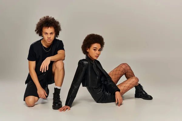 Привлекательный африканский американец брат и сестра в черных нарядах, сидящие на полу — стоковое фото
