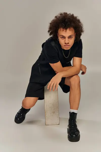 Stylish african american male model in black urban outfit posing actively on gray backdrop — Stock Photo