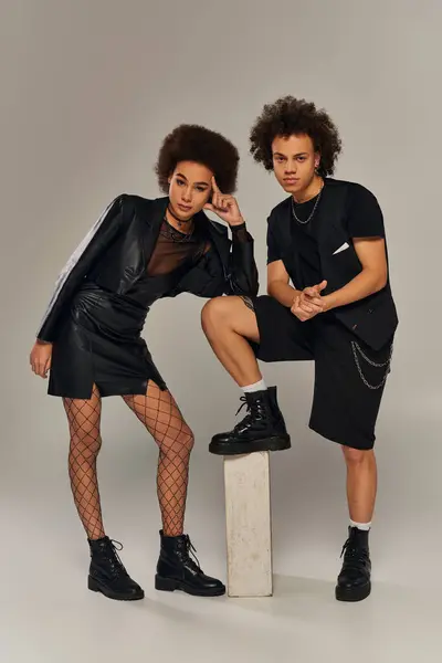 Irmãos americanos africanos na moda em traje urbano preto elegante posando juntos em pano de fundo cinza — Fotografia de Stock