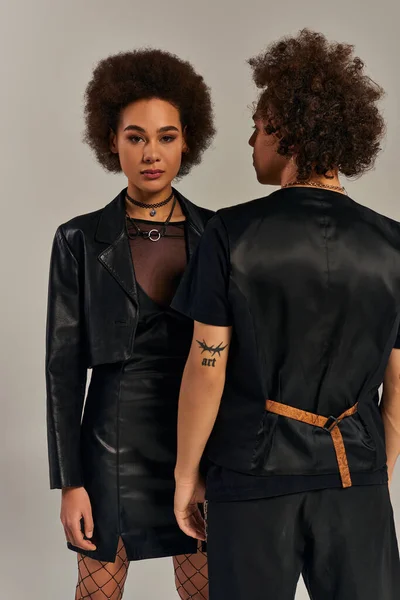 Alla moda fratelli afro-americani in elegante abbigliamento urbano nero in posa insieme su sfondo grigio — Foto stock