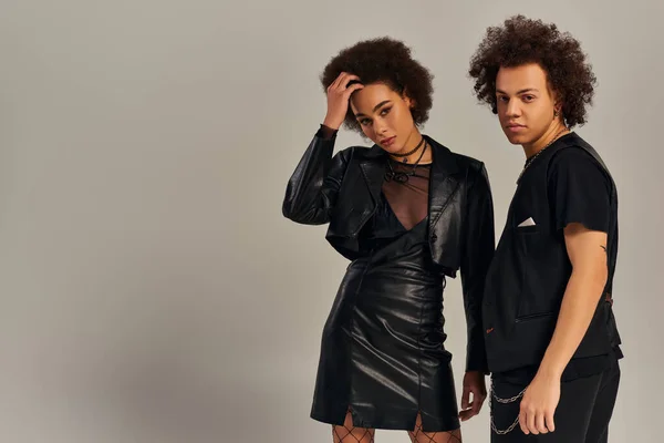 Elegante afrikanisch-amerikanische Geschwister in stylischer schwarzer urbaner Kleidung posieren gemeinsam vor grauem Hintergrund — Stockfoto