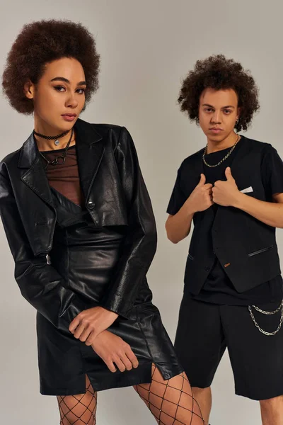 Moda joven afroamericano hermano y hermana en ropa urbana posando activamente sobre gris telón de fondo - foto de stock