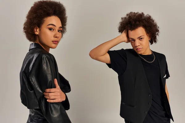 Stylish young african american brother and sister in urban clothes posing together on gray backdrop — Stock Photo