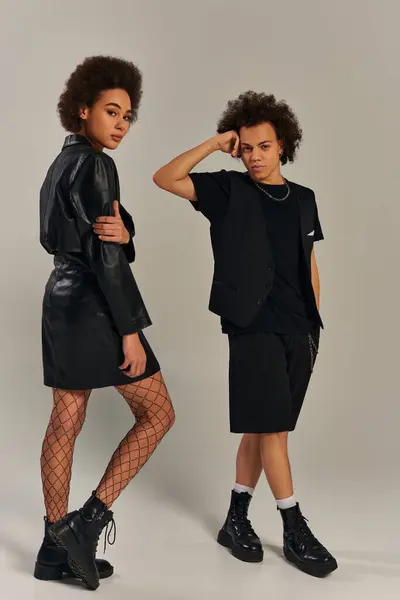 Ansprechende afrikanisch-amerikanische Geschwister in stylischer urbaner Kleidung posieren gemeinsam vor grauem Hintergrund — Stockfoto