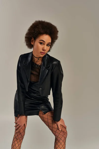 Beautiful african american woman in stylish black attire with fishnet tights posing actively — Stock Photo